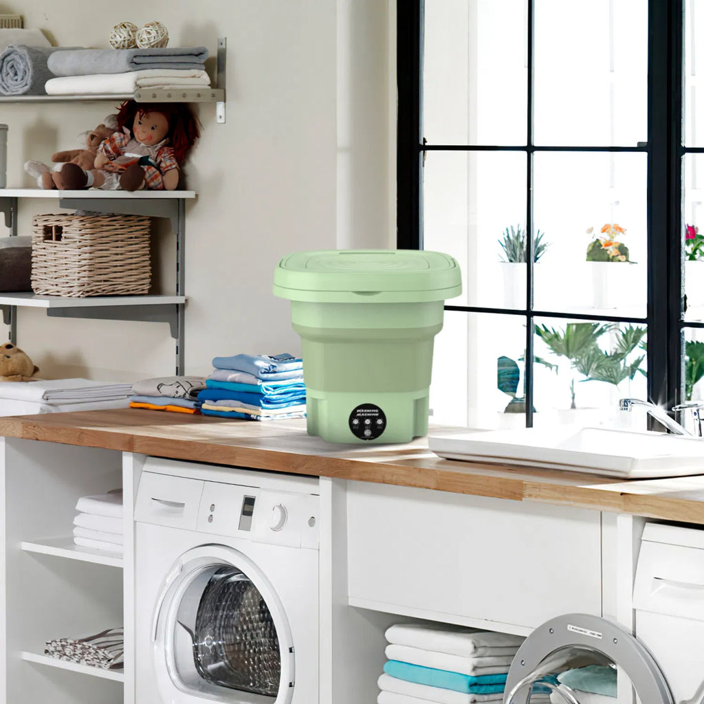 Collapsible green laundry basket on a wooden counter with a washing machine and shelves in the background.